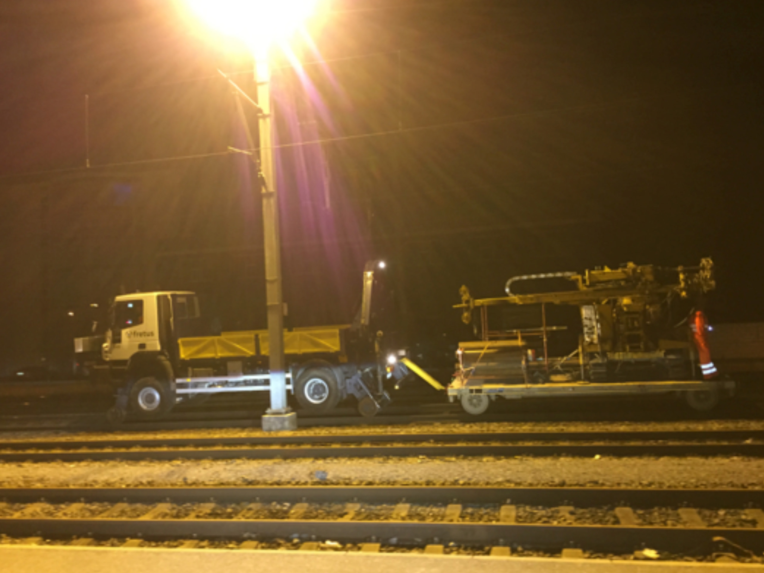 Bahngleise mit LKW und Maschine im Dunklen